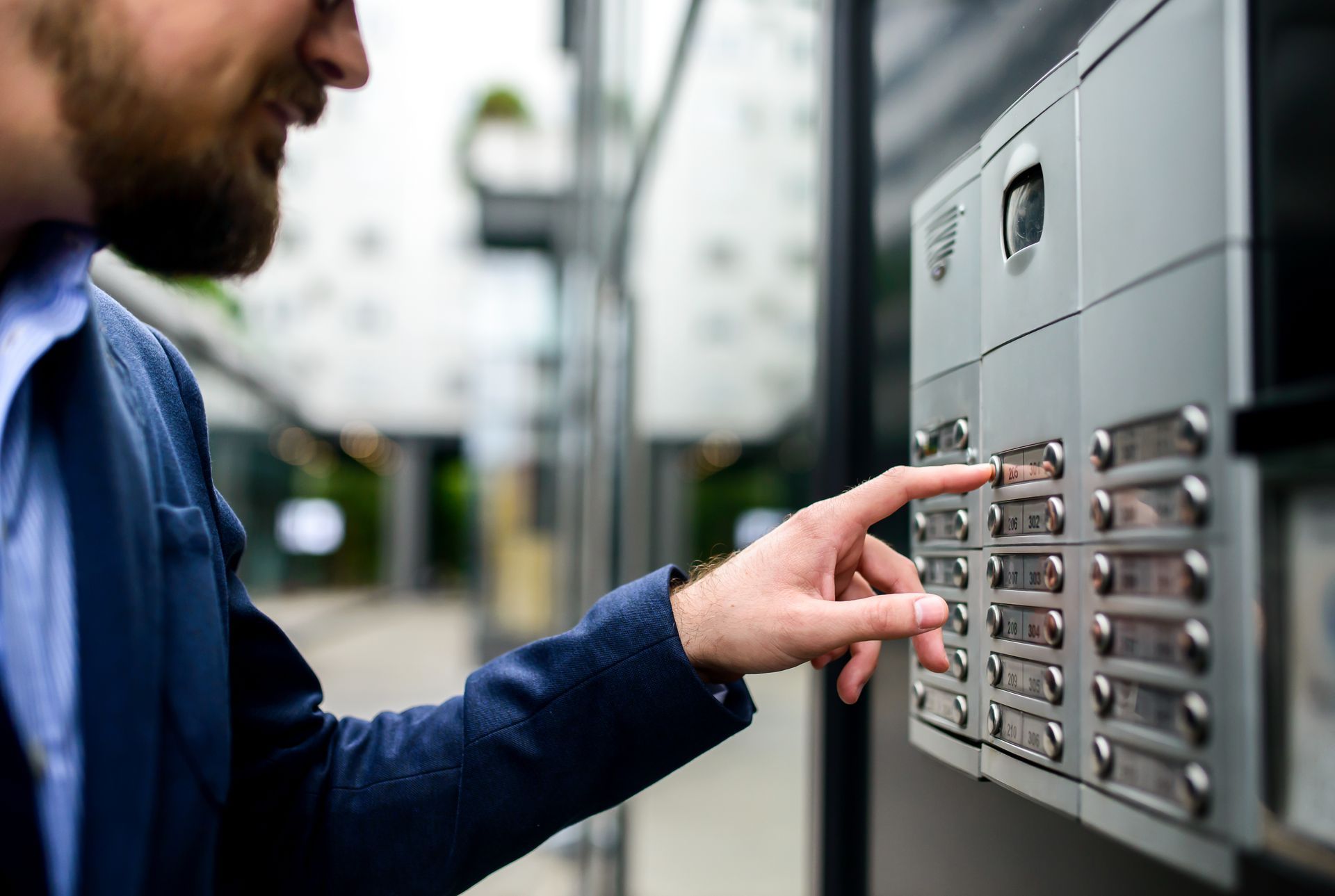 Un homme appuie sur un bouton d'un interphone à l'extérieur d'un bâtiment
