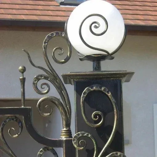 Poteau de portail en métal noir orné d'un motif tourbillonnant et d'un luminaire sphérique blanc