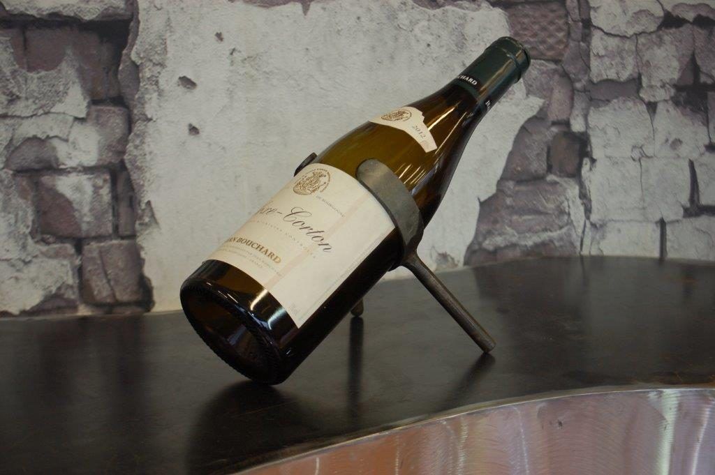 Bouteille de vin dans un support métallique, inclinée sur un bar de présentation en acier