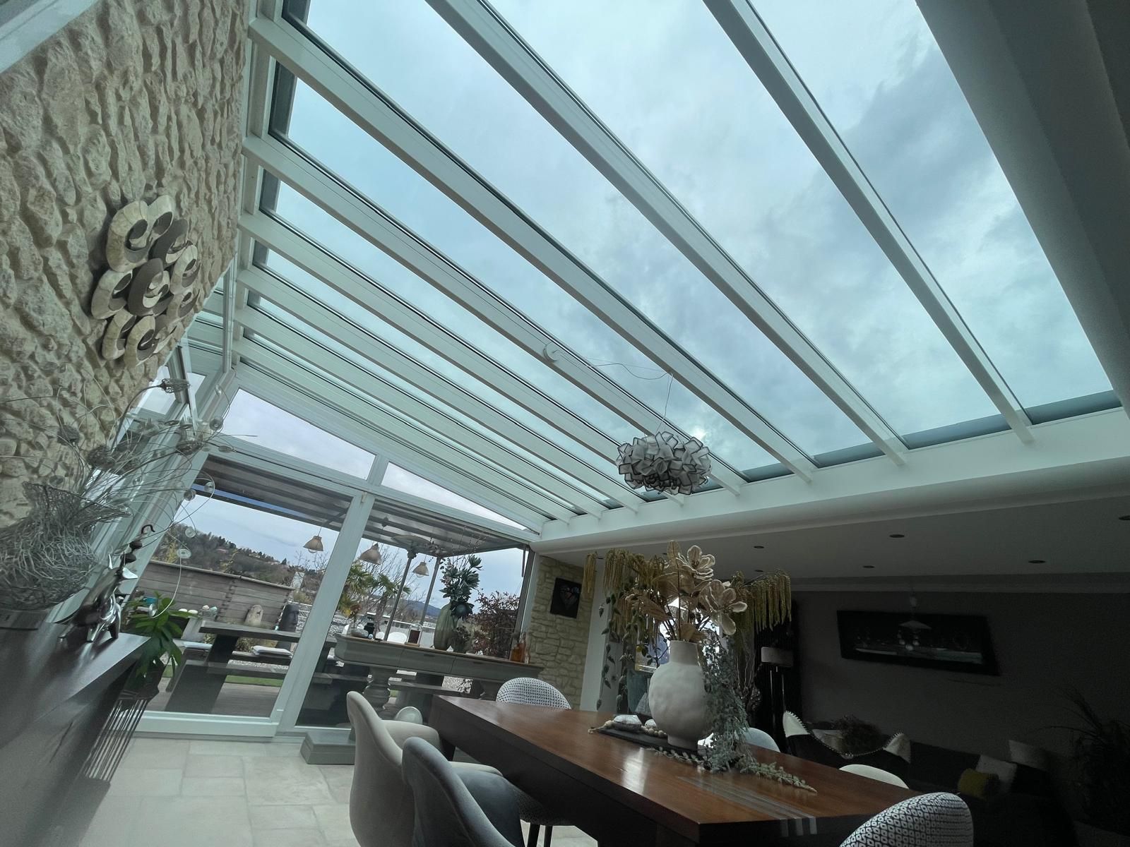 Intérieur d'une véranda avec toit en verre et structure en métal blanc