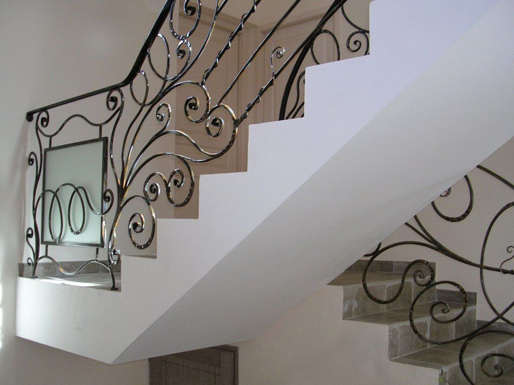 Gros plan sur un portail décoratif en fer forgé orné de motifs de feuilles et de cercles dans des tons bronze et noir