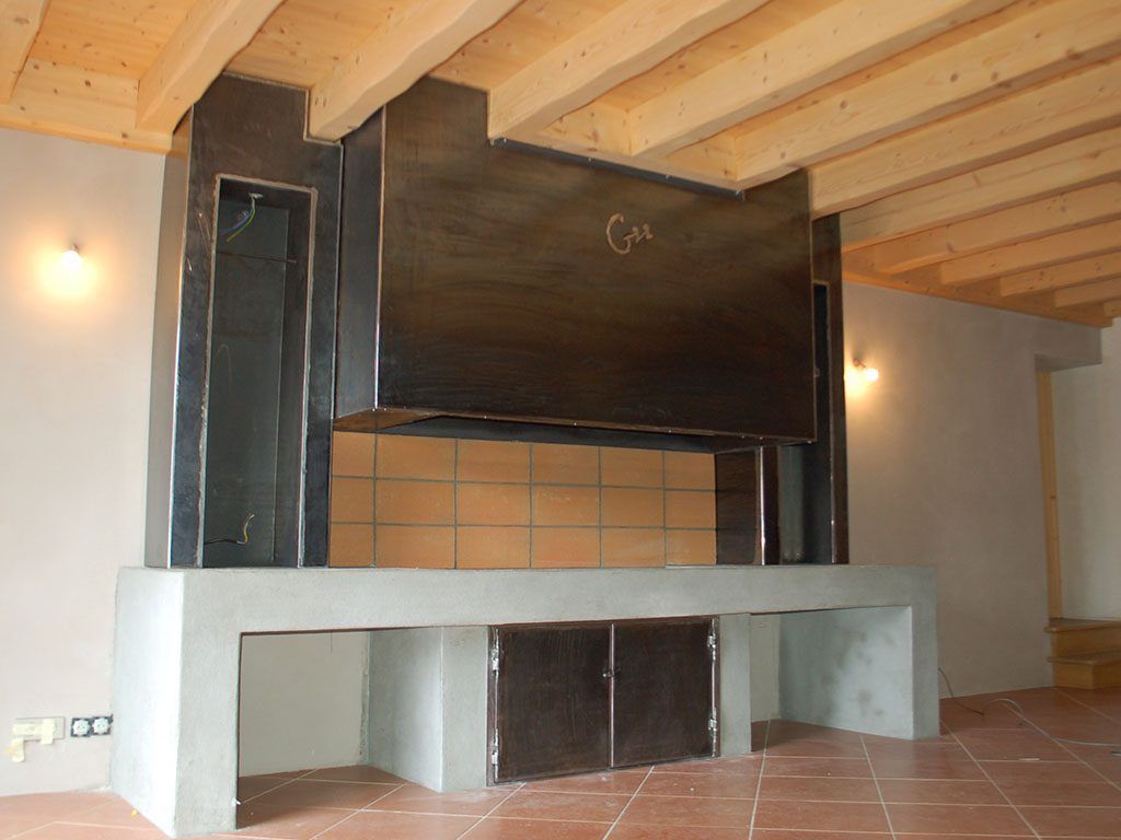 Aménagement de cuisine avec rangements et habillage de hotte en acier et détails en fer forgé