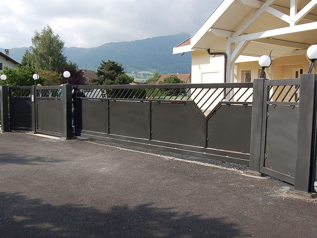 Portail et clôture en métal noir devant une maison