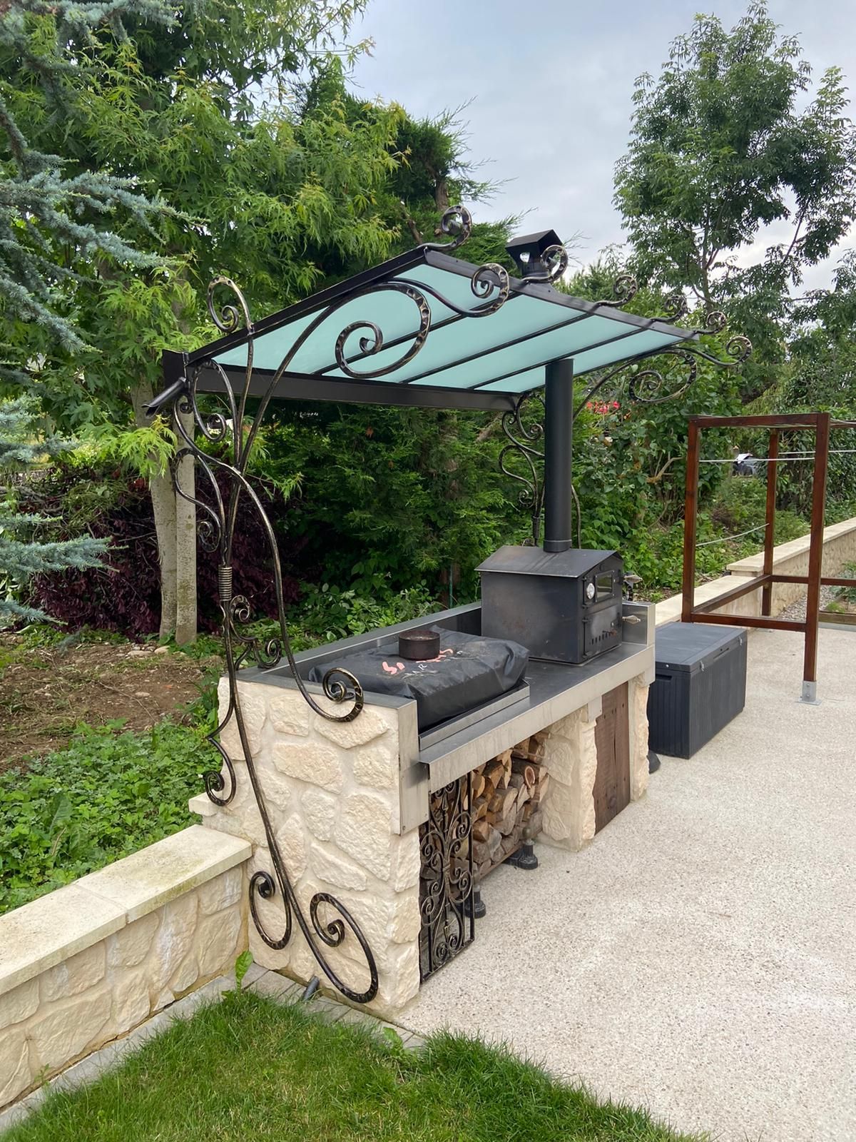 Marquise en fer forgé au dessus d'un barbecue en pierre
