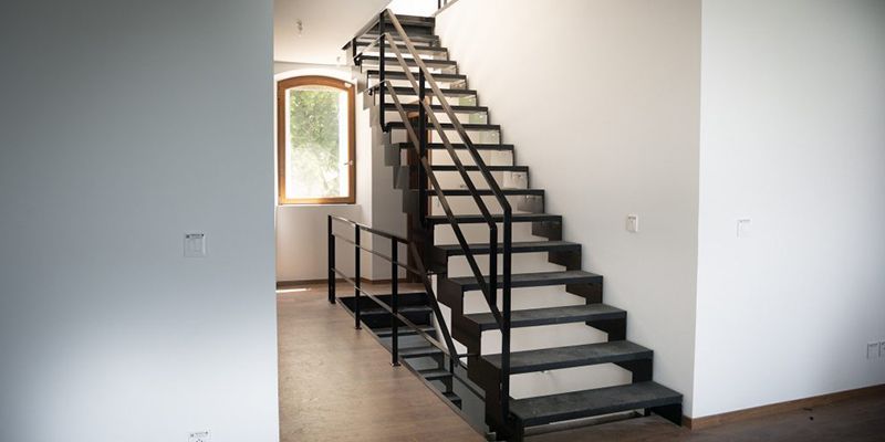 Escalier métallique avec rampes noires près d'une fenêtre
