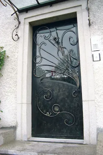 Porte en fer forgé noir ornée de volutes décoratives