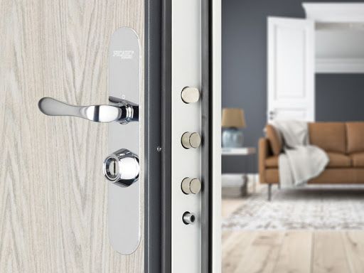 Gros plan sur une porte sécurisée avec poignée argentée et plusieurs verrous