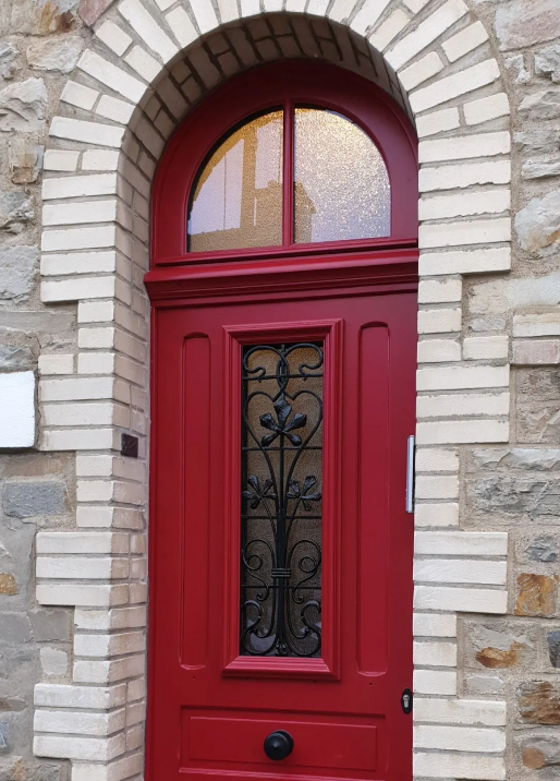 Une porte d'entrée rouge en arc avec des vitrages
