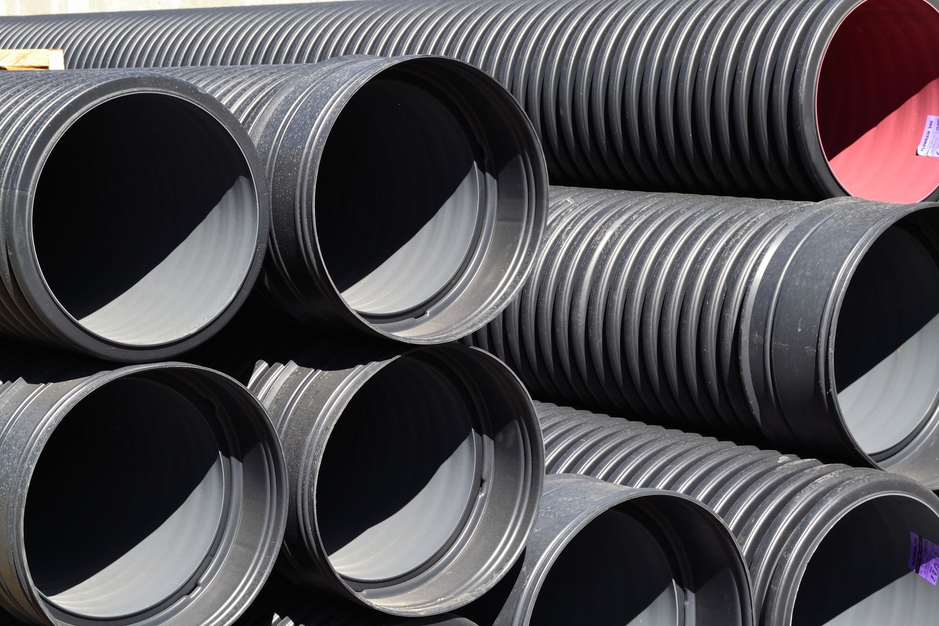 Tuyaux de drainage noirs ondulés empilés avec extrémités ouvertes.