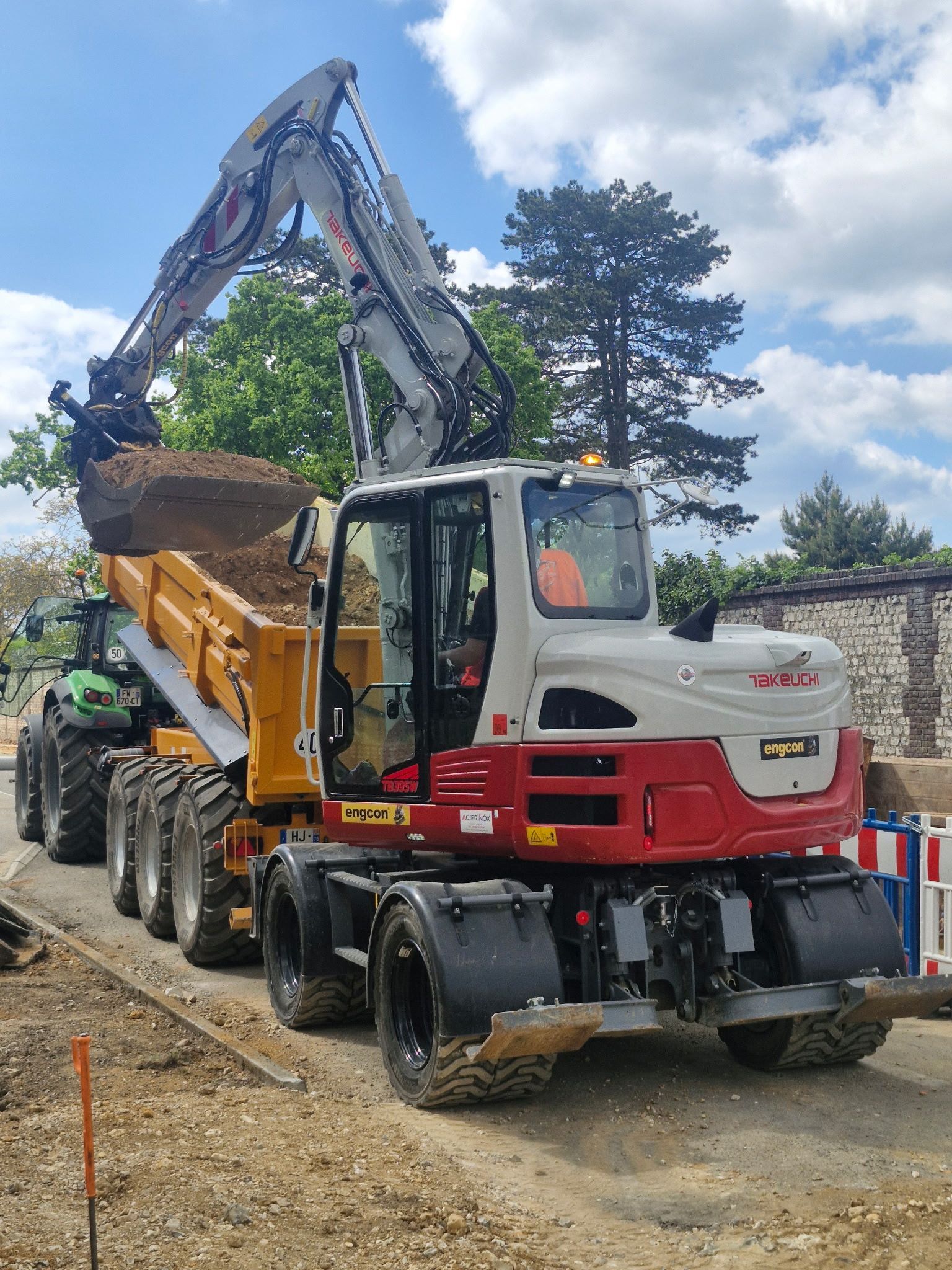 Une excavatrice charge de la terre dans un camion-benne jaune sur un chantier de construction de gravier.