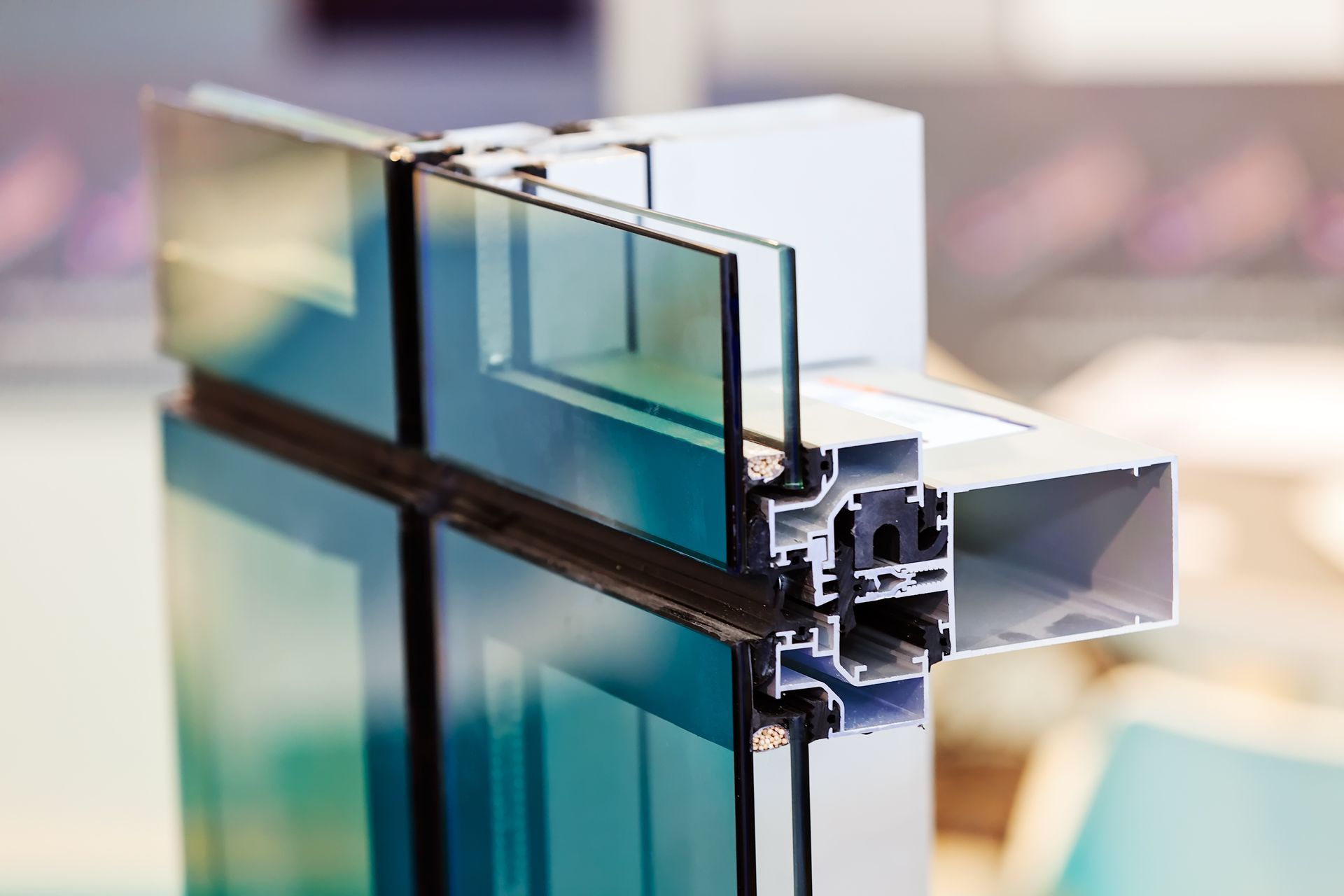 Coupe d'un cadre de fenêtre de mur-rideau en verre teinté bleu et d'un profilé d'extrusion en aluminium.