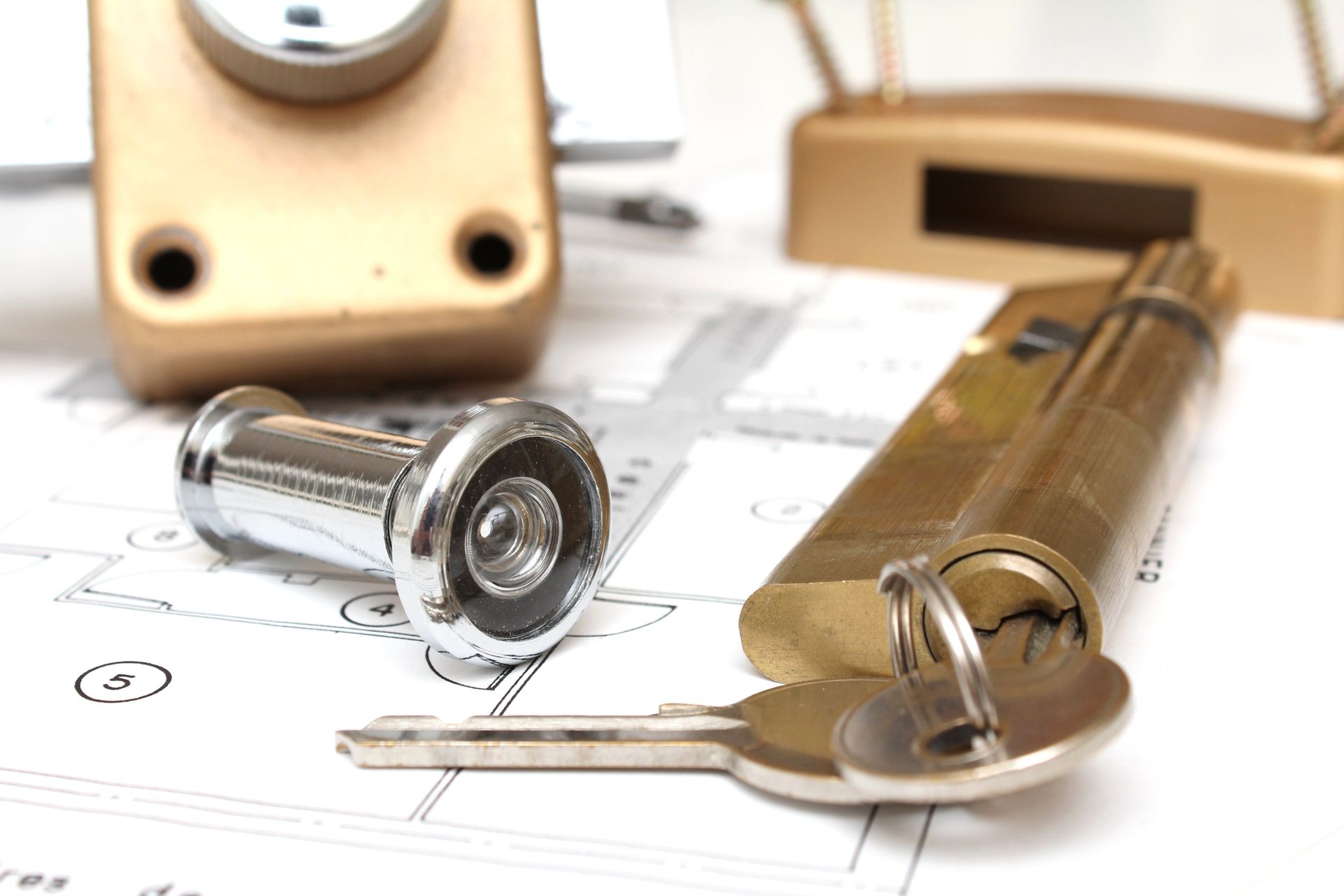 Cadenas et clé en laiton sur un plan, avec un autre cadenas en arrière-plan.
