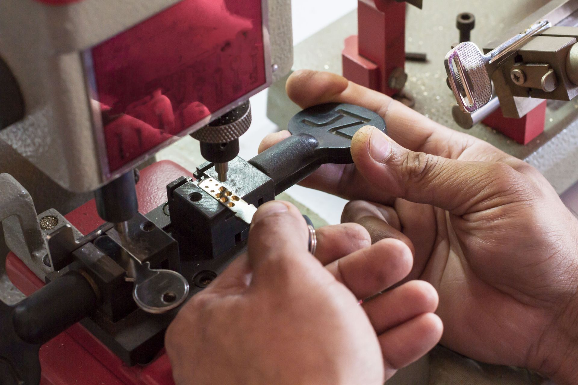 Gros plan de mains ajustant une clé noire sur une machine rouge dans un atelier.