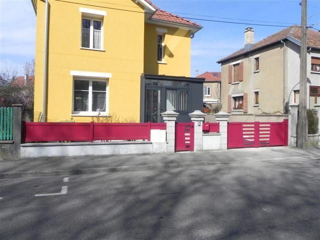 Des clôtures et un portail rouge.