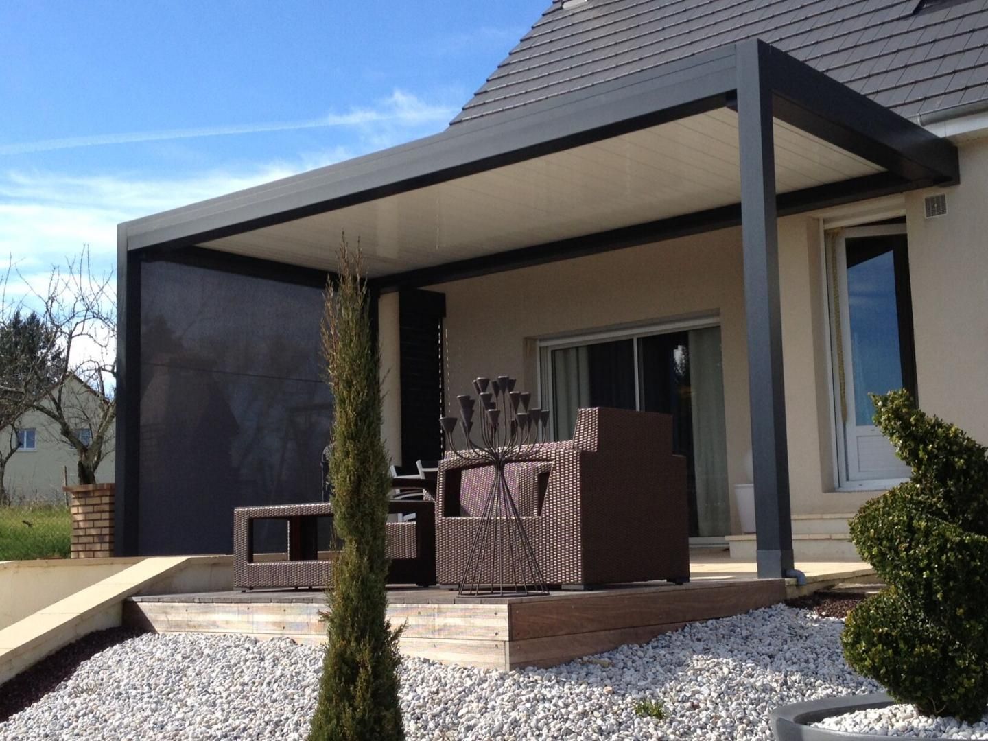 Une pergola abritant un salon de jardin.