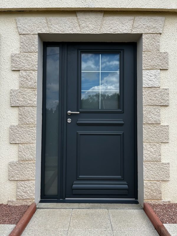 Une porte d'entrée noire avec de la pierre autour.