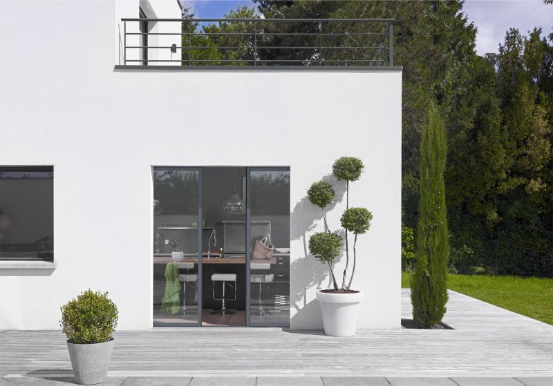 Une maison blanche avec une baie vitrée.