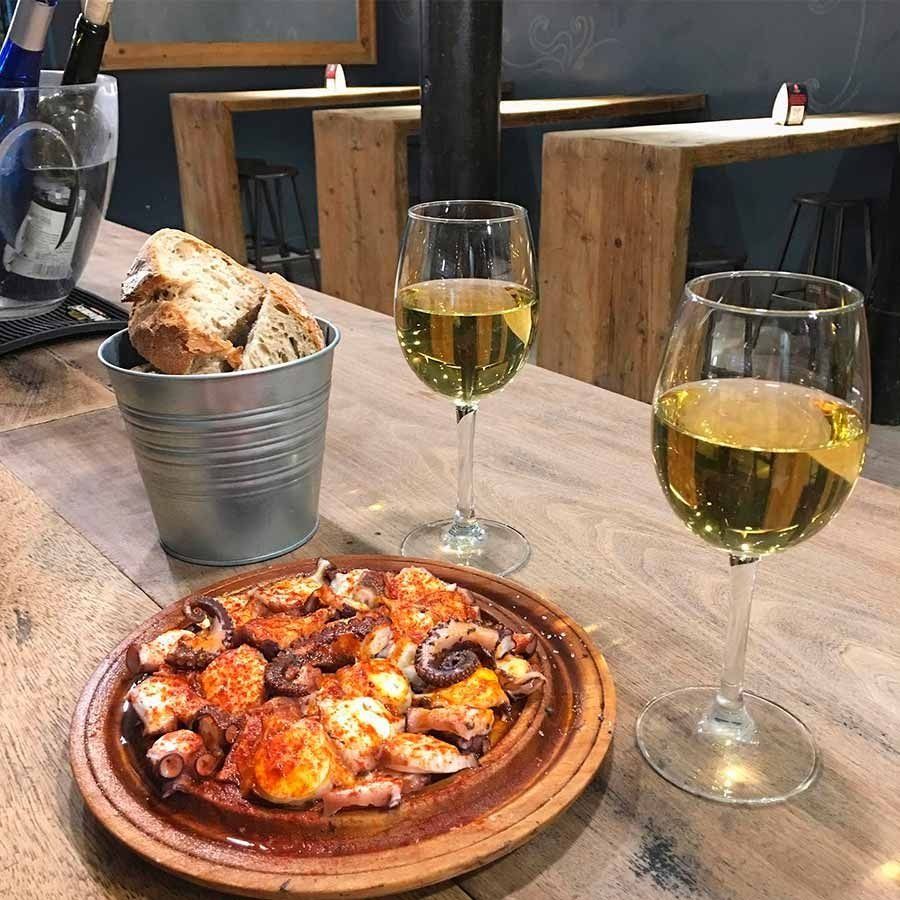 Un plato de comida y dos copas de vino en una mesa de madera.