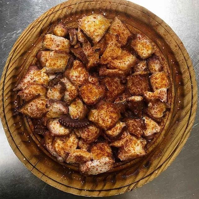 Un cuenco de madera lleno de trozos de comida sobre una mesa.