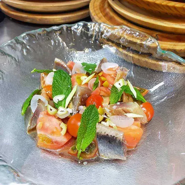 Un primer plano de una ensalada en un recipiente de vidrio sobre una mesa.