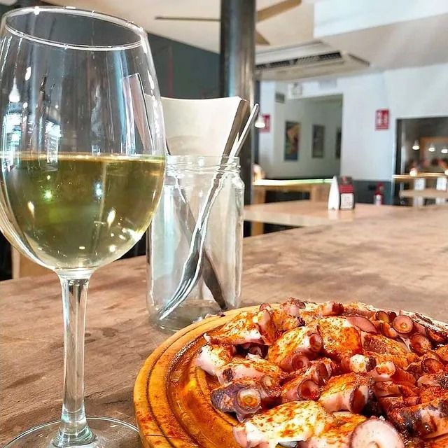 Un plato de comida junto a una copa de vino