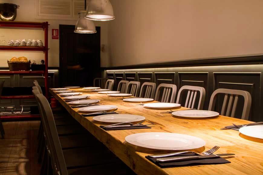 Una mesa larga de madera con platos y cubiertos encima en un restaurante.