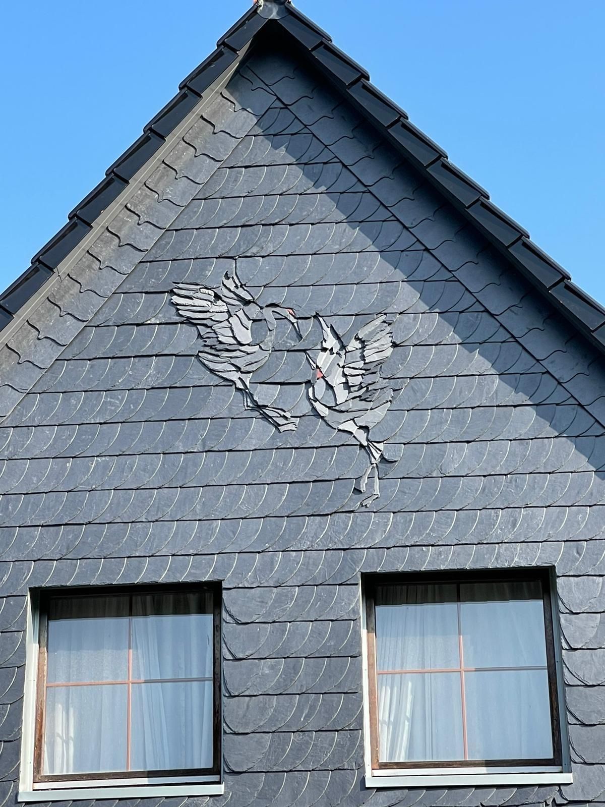 Ein Haus mit einem Vogel auf dem Dach und zwei Fenstern