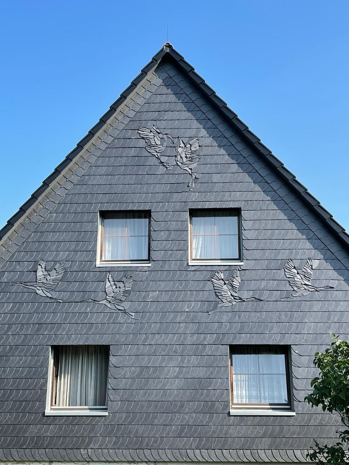 Ein Haus mit einem dreieckigen Dach und drei Fenstern