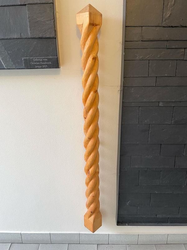 Eine gedrehte Holzstange hängt an einer Wand