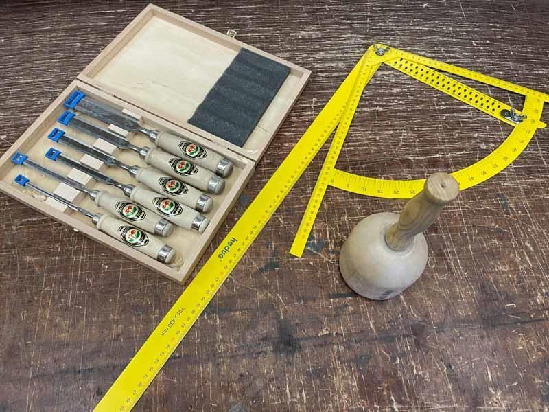 Ein Satz Werkzeuge, darunter ein Lineal und ein Hammer auf einem Holztisch