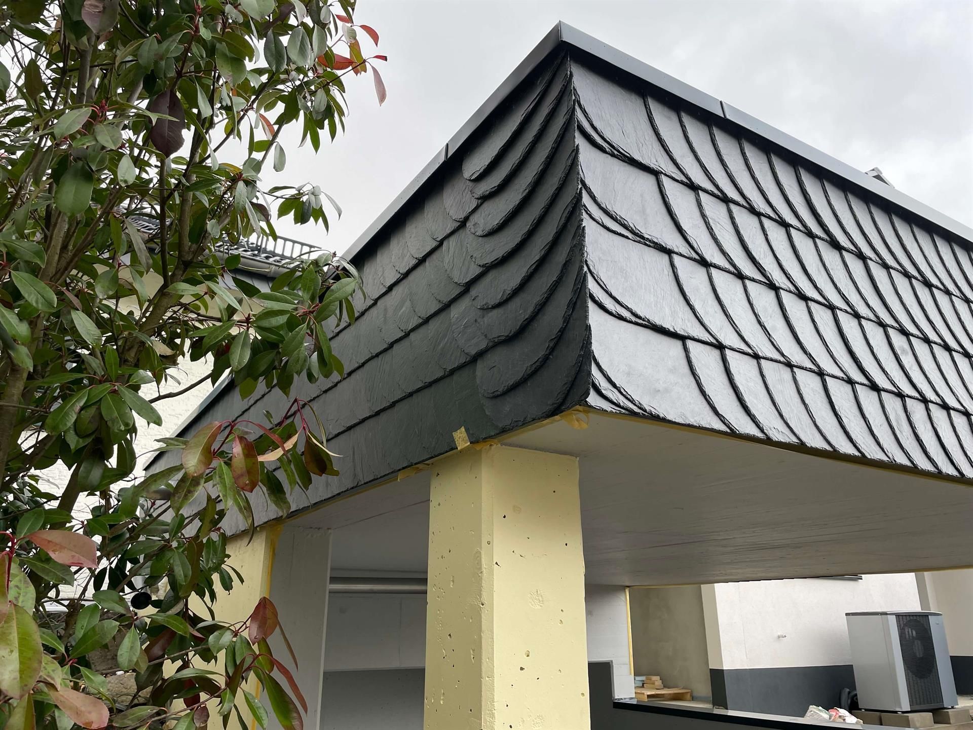 Ein Gebäude mit Schieferdach und einem Baum im Vordergrund