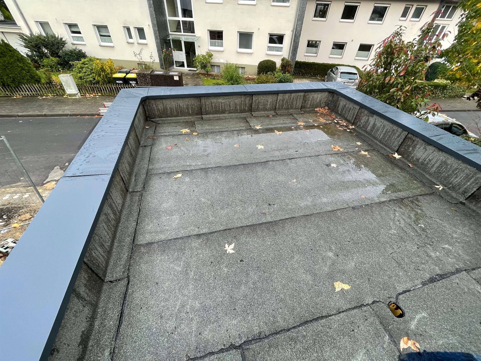 Eine Person steht auf einem Dach, im Hintergrund ist ein Gebäude zu sehen.