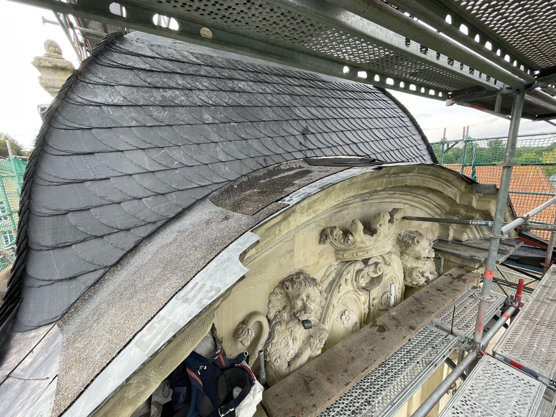 Das Dach eines Gebäudes wird mithilfe eines Gerüsts repariert.