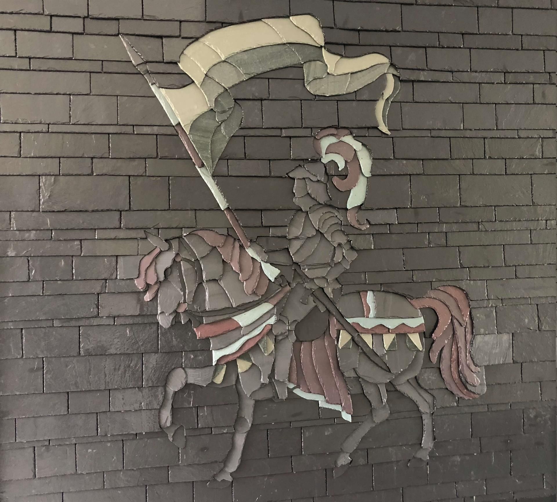 Ein Ritter auf einem Pferd, der eine Flagge an einer Ziegelmauer hält