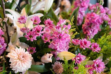 Nahaufnahme eines farbenfrohen Blumenarrangements mit rosa und weißen Blüten, darunter Lilien und Chrysanthemen.