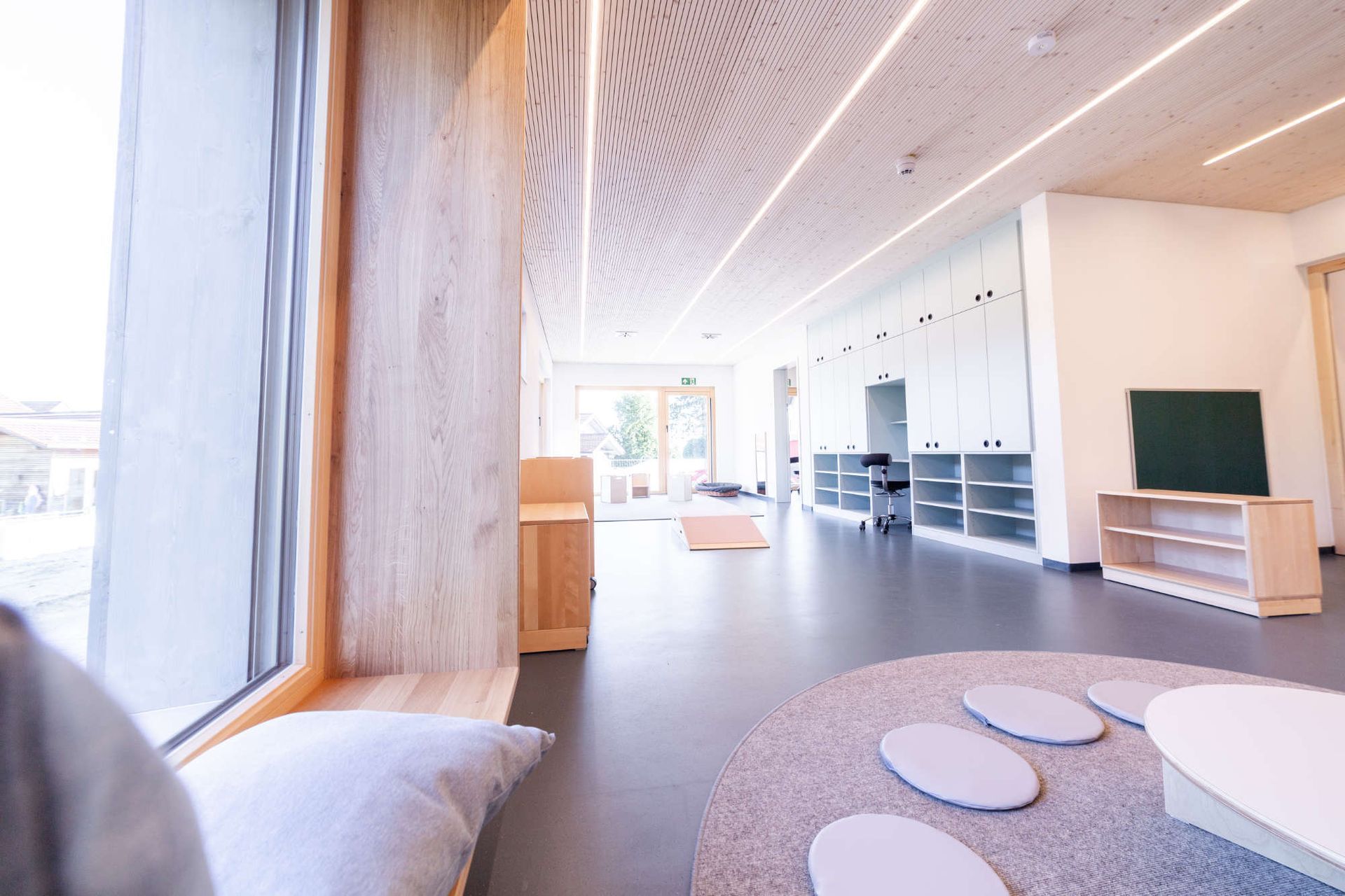 Zimmereinrichtung in hellen grau und braun Tönen mit runden Sitzkissen und Teppich auf dem Boden