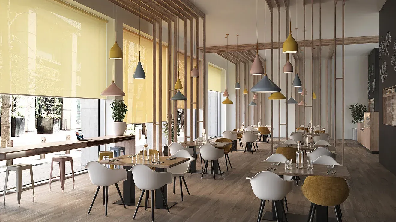 Einrichtung eines Restaurants mit hellen Pastelltönen in Gelb, Rosa, Blau-Grau mit Wandverkleidungen aus Holz und vielen hängenden Lampen