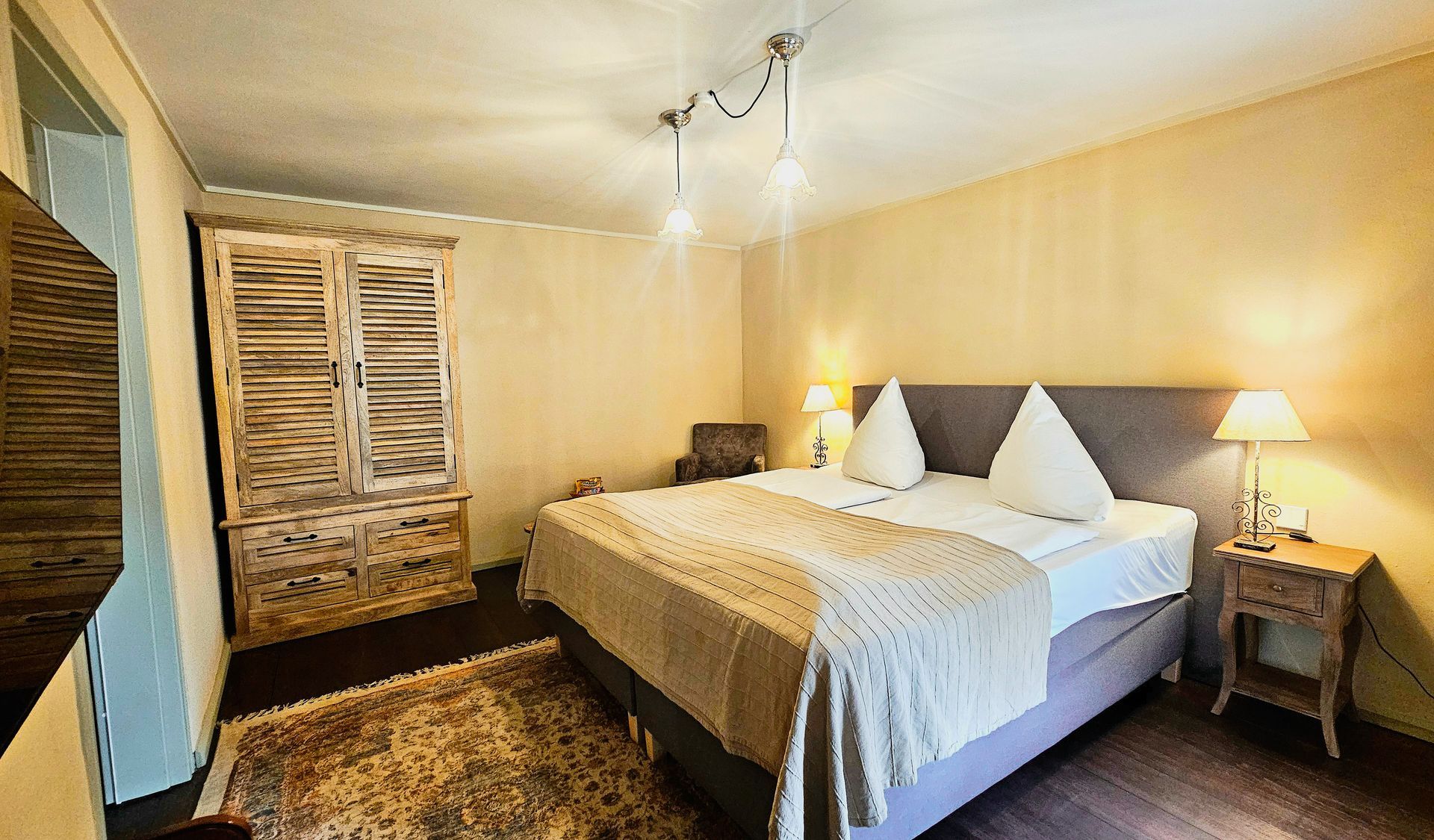 Schlafzimmer mit Doppelbett, Kleiderschrank, Teppich und Nachttisch mit Lampe.