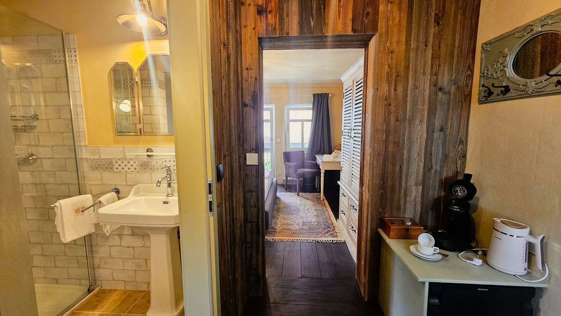 Innentür mit rustikaler Holzvertäfelung, die zu einem Schlafzimmer führt, in dem sich links ein Badezimmer befindet.