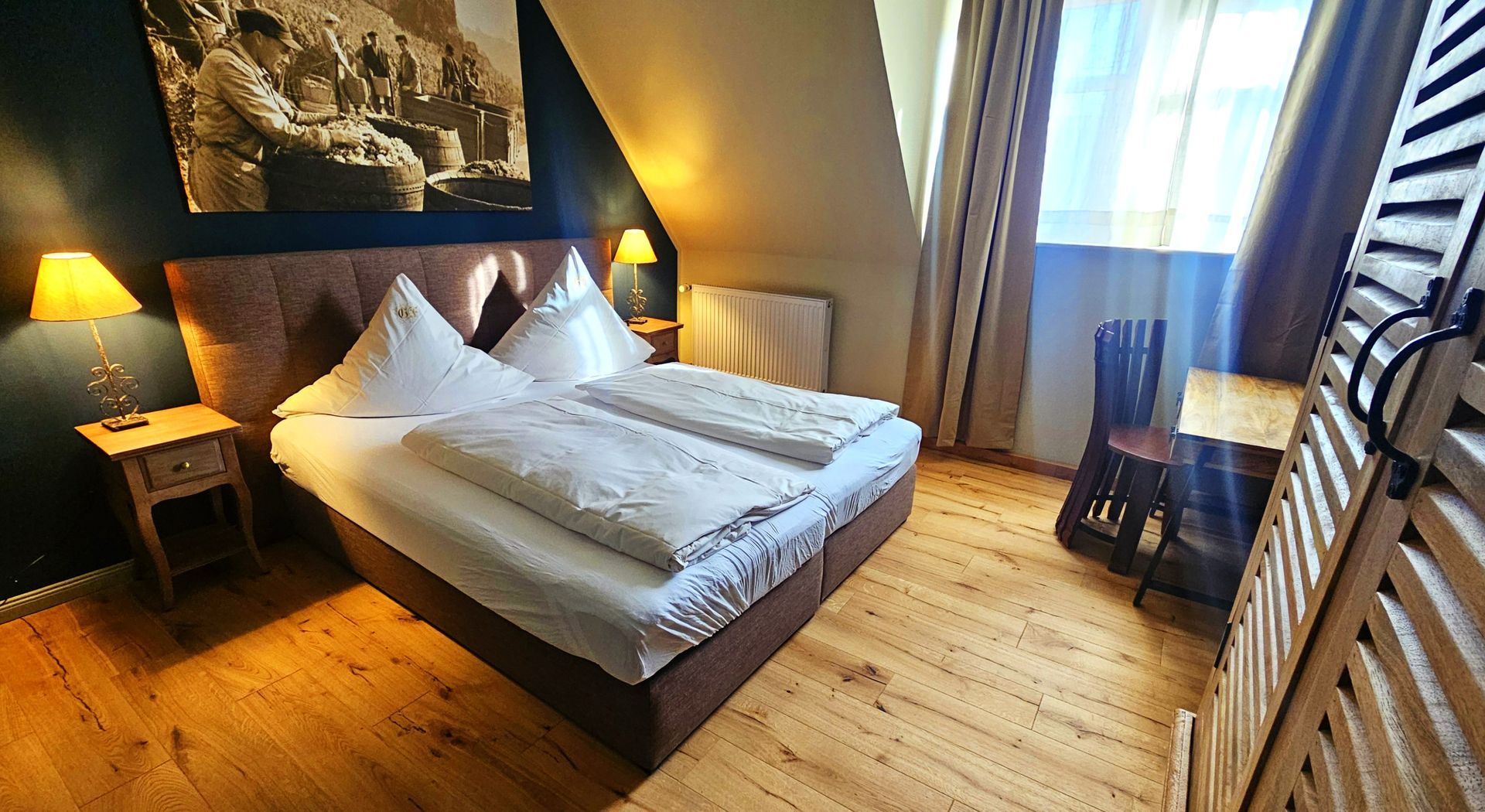 Schlafzimmer mit braunem Bett, Holzboden und einem hohen Holzschrank auf der rechten Seite.