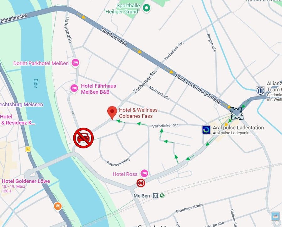 Karte mit einer roten Markierung in der Nähe eines Flusses und beschrifteten Straßen sowie mehreren roten Routenmarkierungen und Symbolen.