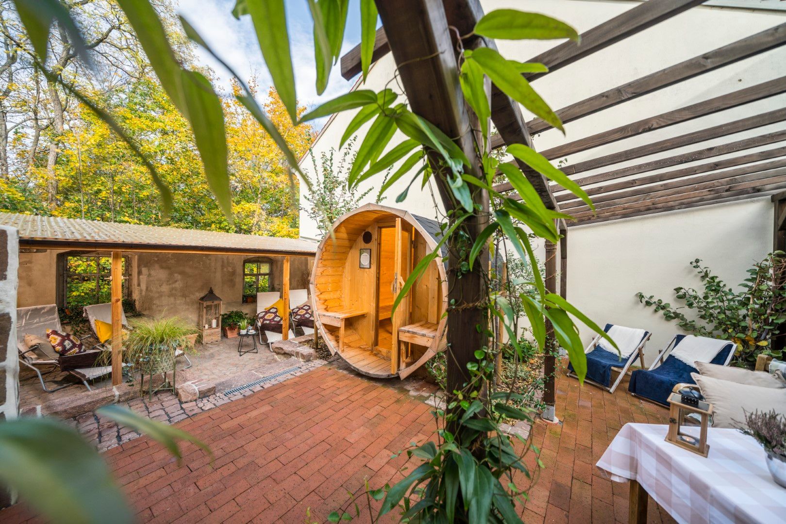 Wellnessbereich im Freien mit Holzsauna, Sitzgelegenheiten und Grünanlagen.