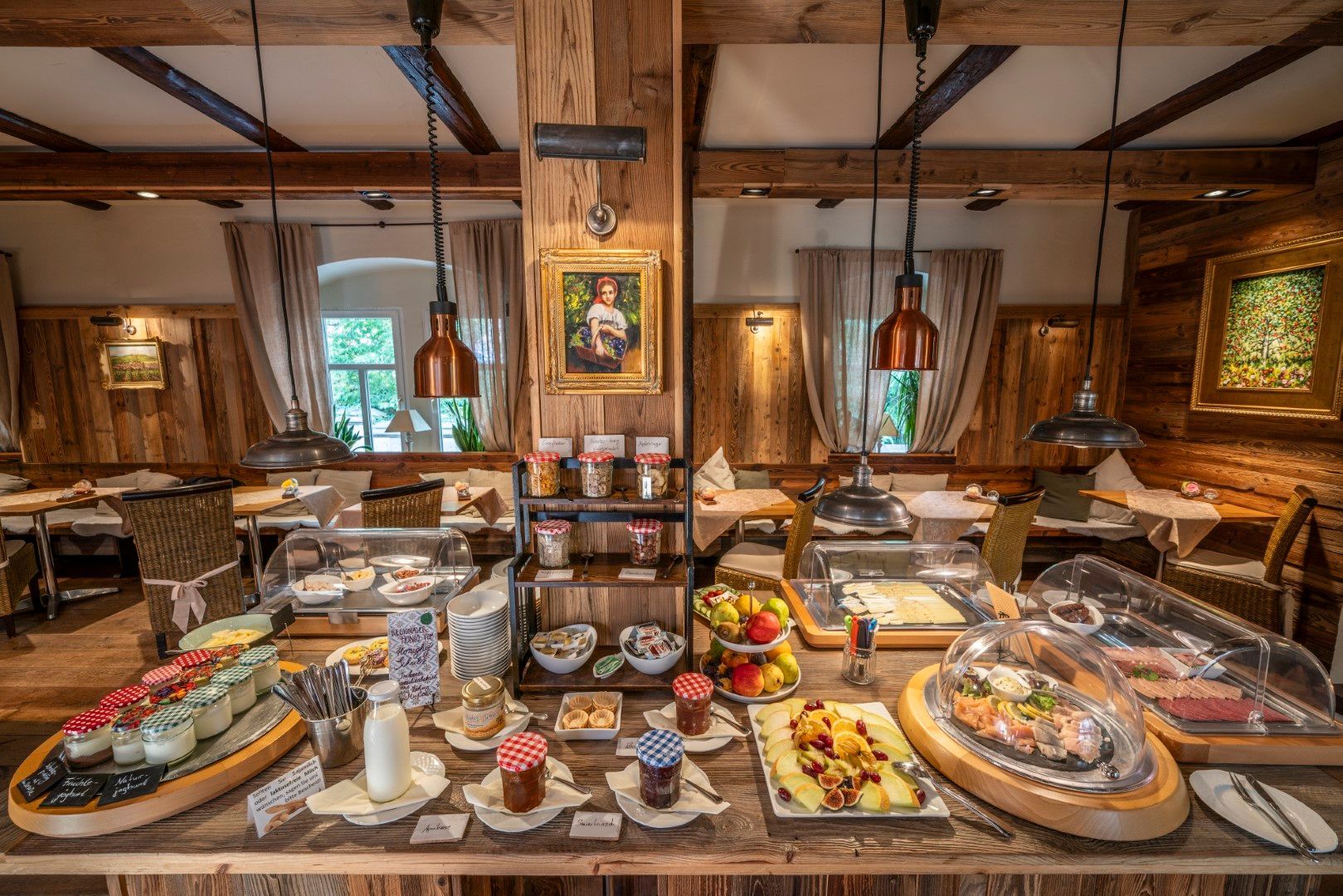 Frühstücksbuffet in einem rustikalen Speisesaal mit verschiedenen Speisen, die auf einer Holztheke präsentiert werden.
