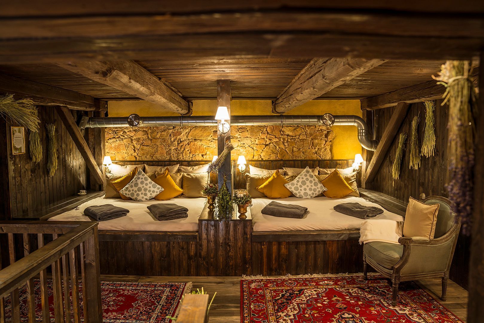 Gemütlicher, rustikaler Loungebereich mit niedrigen Sitzmöbeln, Kissen und Teppichen. Holzbalken und -wände, sanfte Beleuchtung.