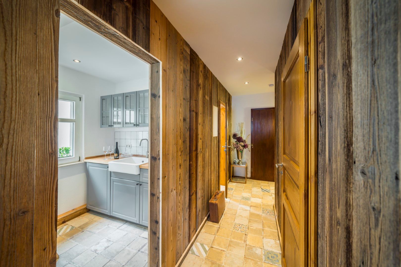 Holzgetäfelter Flur mit Zugang zur Küche und einer geschlossenen Tür auf der rechten Seite.