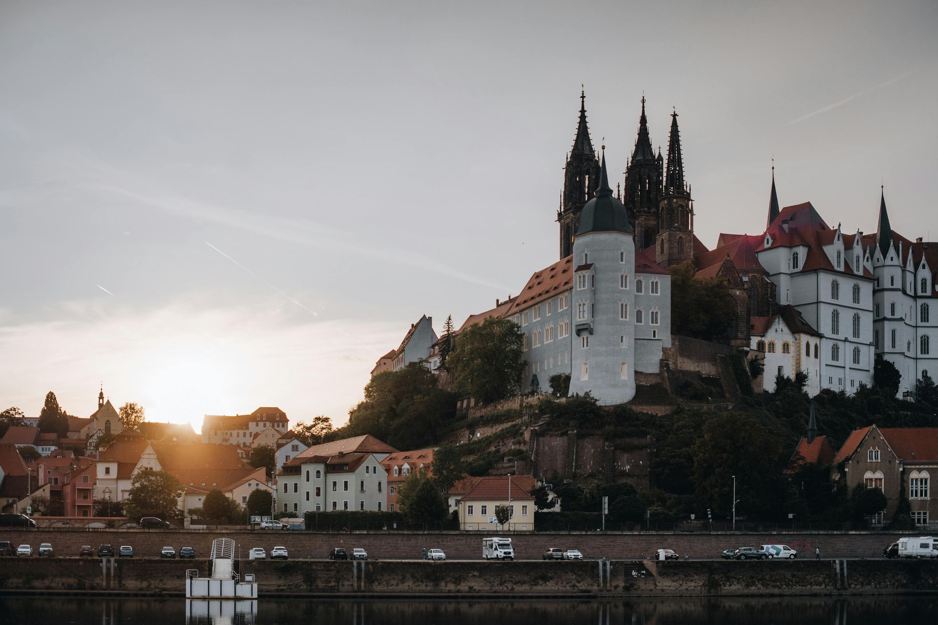 Bei Sonnenuntergang spiegeln sich Burg und Stadt auf einem Hügel im Wasser.