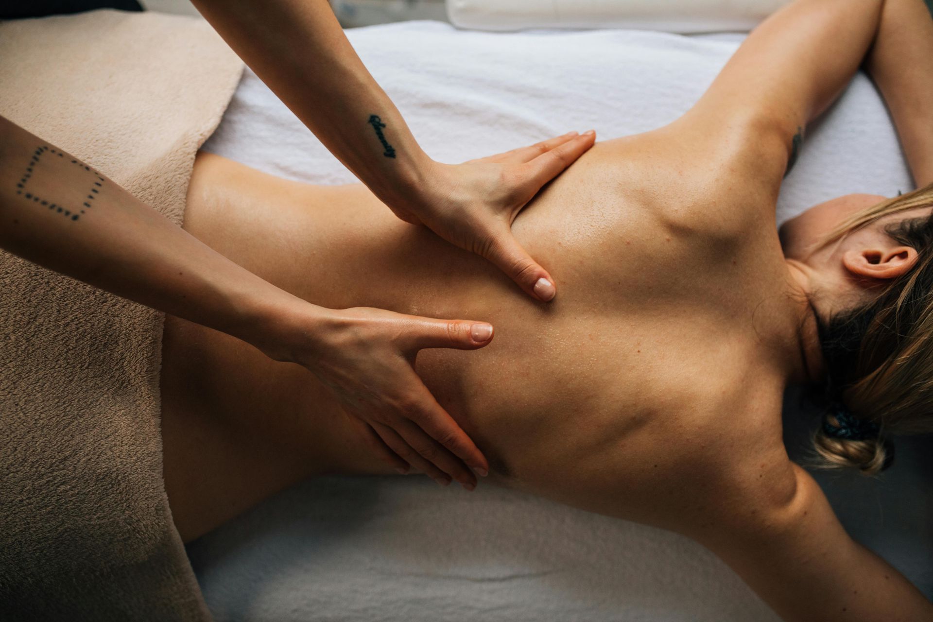 Eine Person erhält eine Rückenmassage von einem Therapeuten, der mit den Händen Druck auf den oberen Rücken ausübt.
