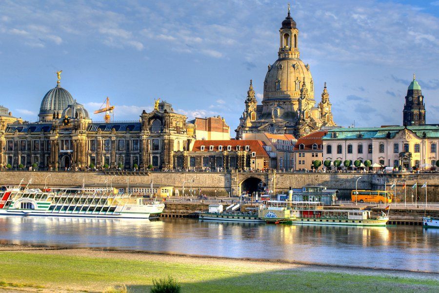 Stadtbild von Dresden, Deutschland, mit Gebäuden am Wasser, Booten auf der Elbe und der Frauenkirche.