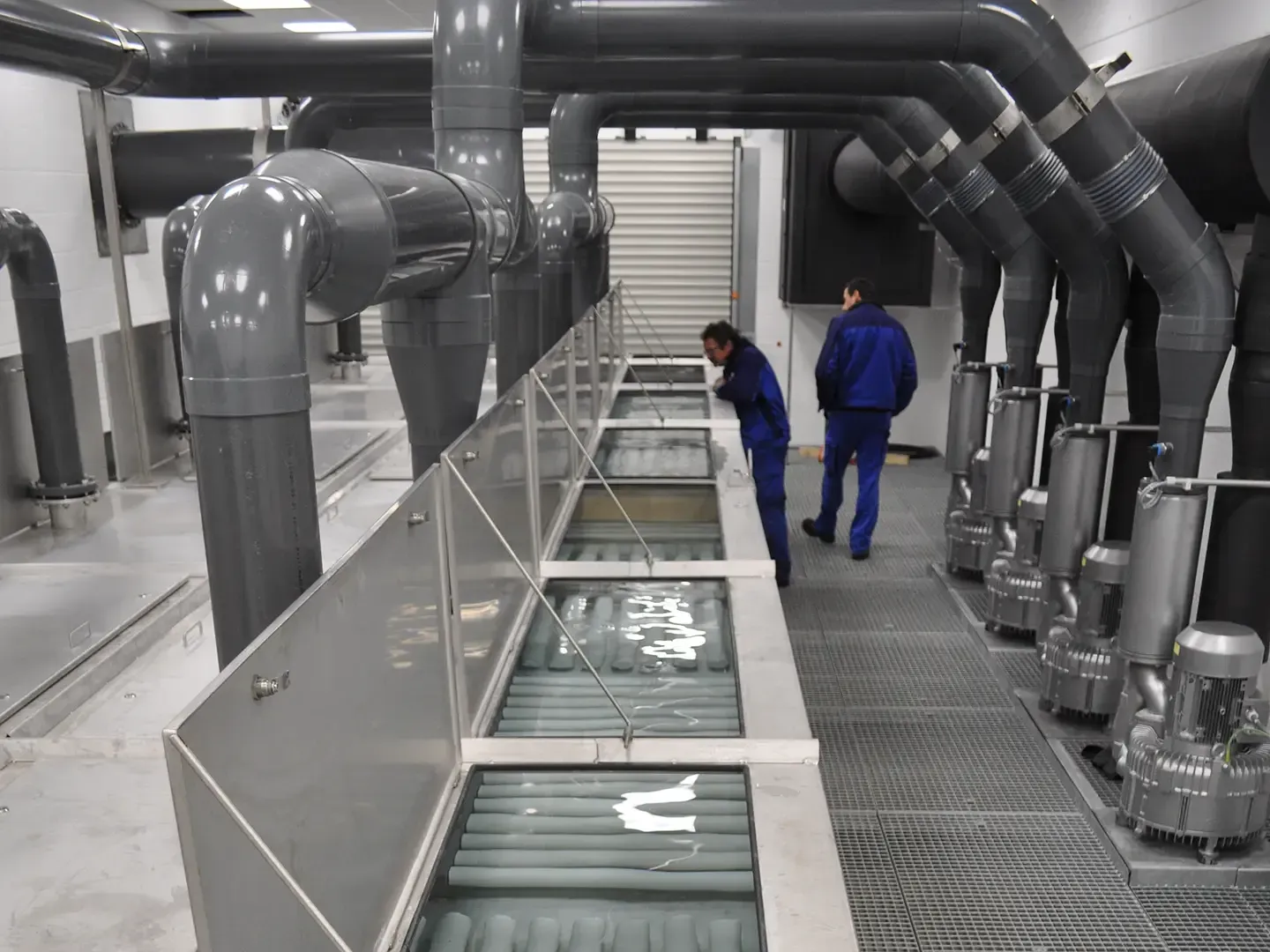 Zwei große grüne industrielle Wasserfiltertanks mit Rohren in einem Hauswirtschaftsraum.