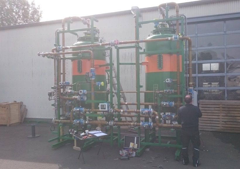 Zwei große grüne und orange Industrietanks mit Kupferrohren und eine Person davor.